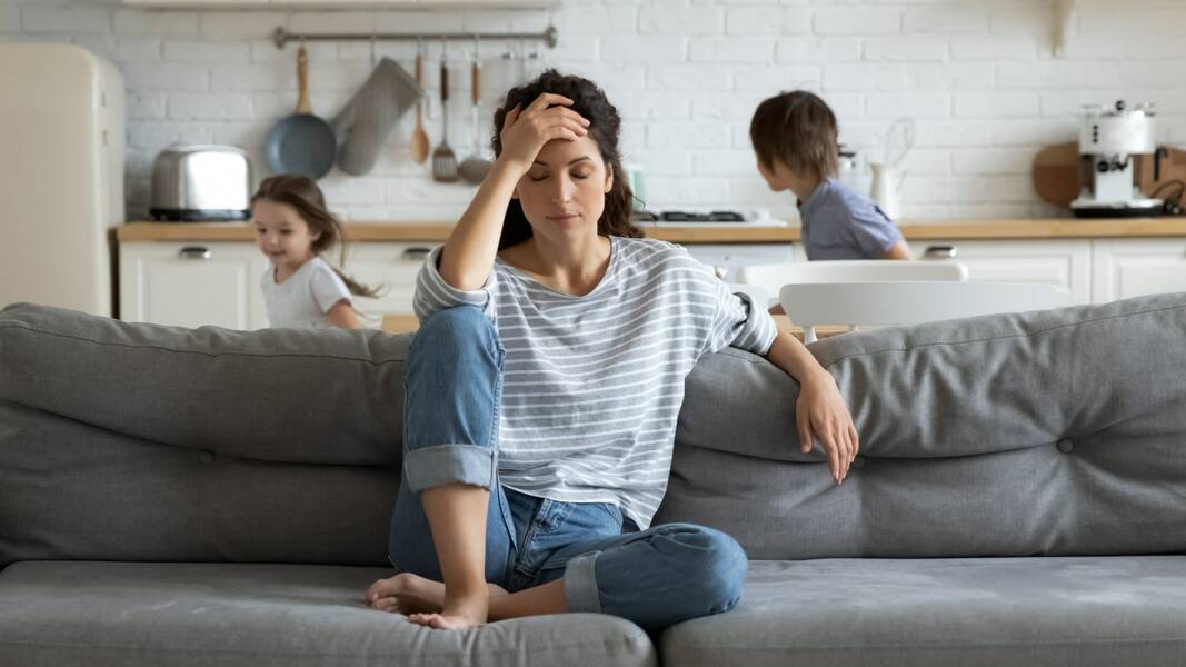 Parent assis sur un canapé pendant que les enfants jouent derrière