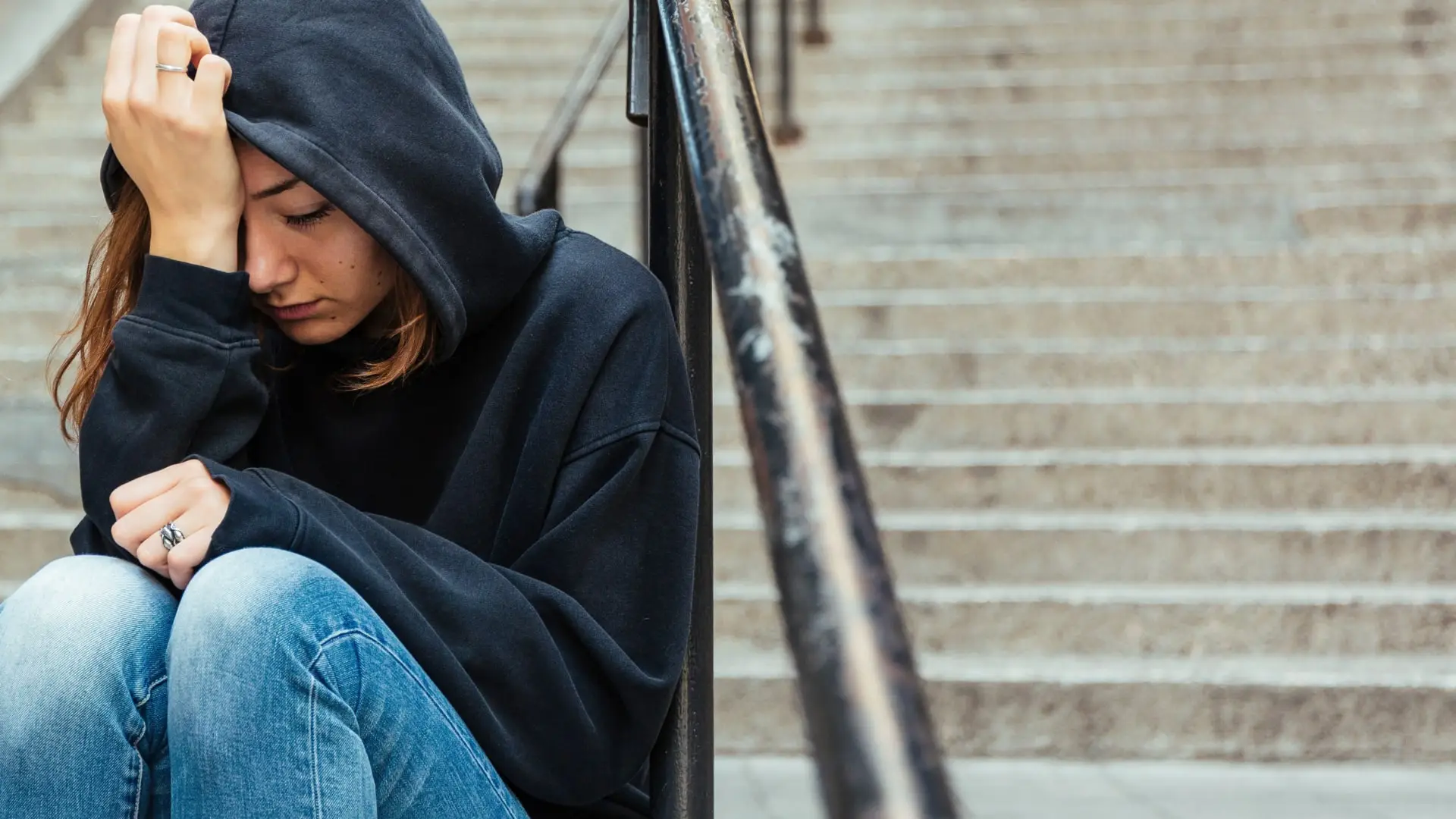 Person sitting on outdoor steps with head down